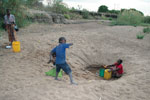 Thumbnail of A family searching for water by digging deep into a dried riverbed during the dry season in northeastern Zambia.