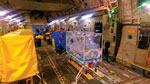 Thumbnail of Multiple Air Transportable Isolator patient transport systems on a single aircraft (Boeing C-17 Globemaster). A single isolator is set up for the confirmed viral hemorrhagic fever case-patient; 2 additional isolators (left, covered) are available for the 2 exposed patients should they deteriorate or become symptomatic in flight.